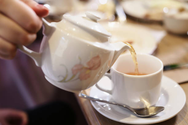 istock Morning tea breakfast. Kettle pouring boiling water into a cup during breakfast in morning sunlight 1133329105
