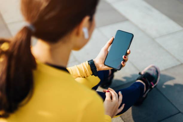 giovane donna sportiva che si riposa e controlla i risultati sull'app per smartphone dopo l'uscita urbana in città - running jogging asian ethnicity women foto e immagini stock