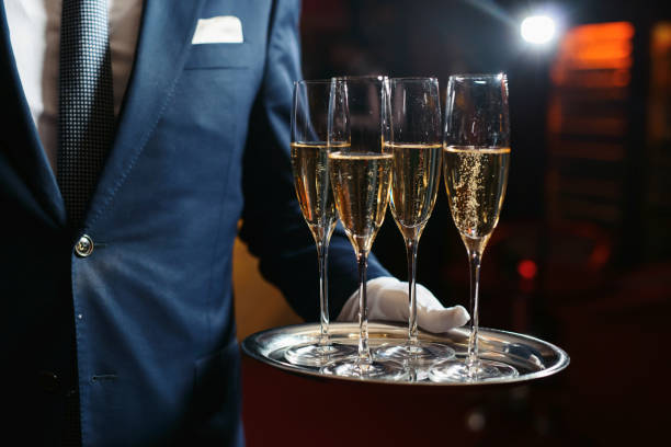 официант, обслуживающий шампанское на подносе - waiter butler champagne tray стоковые фото и изображения
