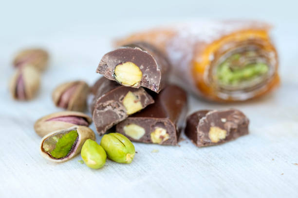 Eastern Turkish sweets with pistachios on a white wooden background. Chocolate candy with pistachios, baklava and pistachio nuts around.