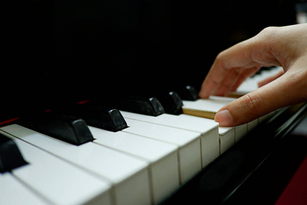 istock close-up female hand playing grand piano. 1133332990