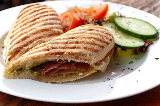 Ham panini with side salad on wooden table at restaurant