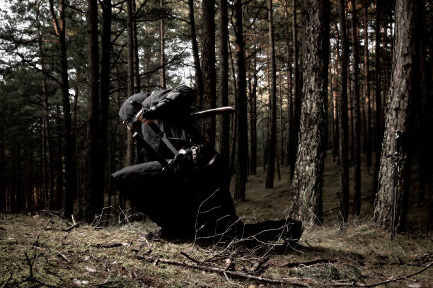 istock Man in assassins suit and sword standing in the forest. 1133335749