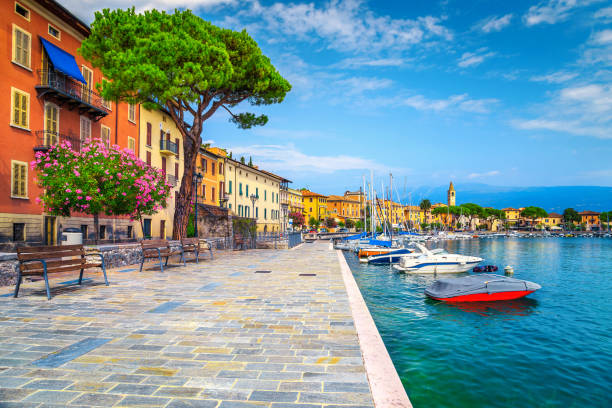 Promenade with colorful mediterranean oleander flowers, Toscolano-Maderno, Italy Wonderful paved walkway with colorful mediterranean flowers. Luxury yachts, boats and sailing boats in the majestic harbor of Toscolano-Maderno, lake Garda, Lombardy region, Italy, Europe lake garda photos stock pictures, royalty-free photos & images