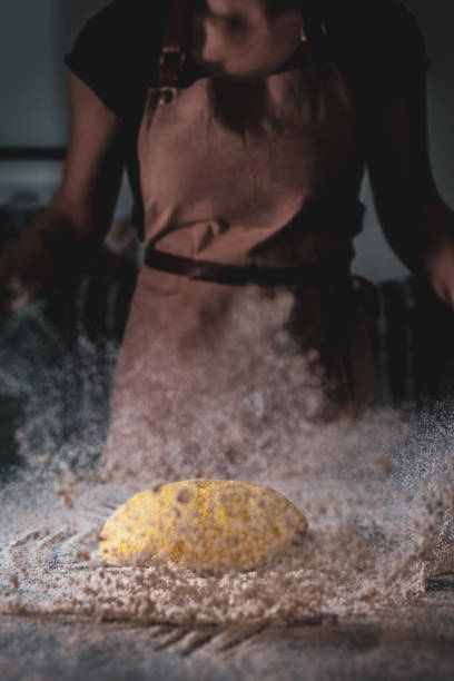 Chef dropping dough and flying flour on wooden table background