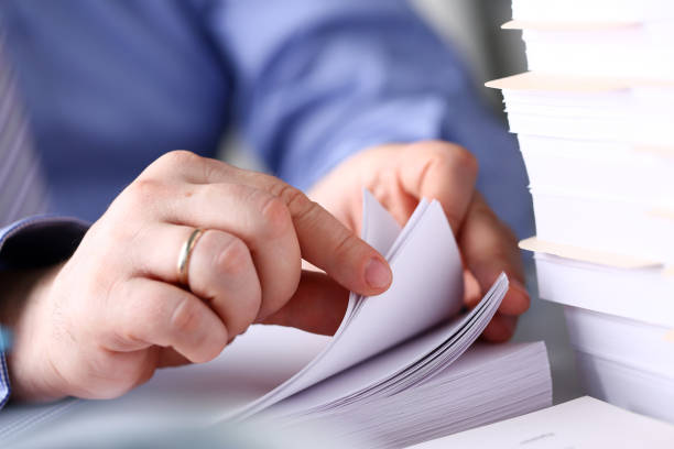 istock Clerk arm bend over pages in pile of documents closeup 1133342339