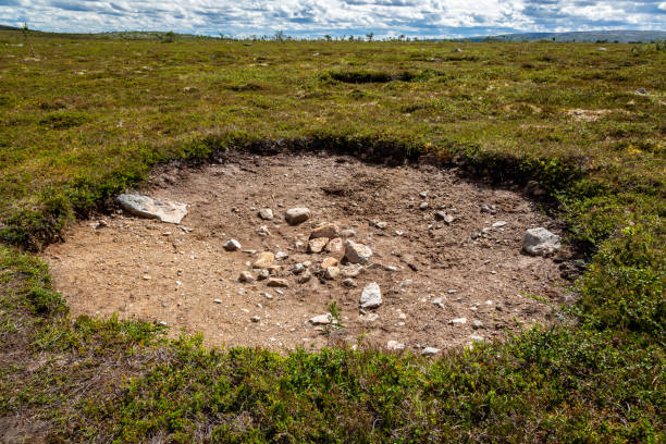 Flat highland landscape view of a large hole in the ground surrounded by green vegetation. stock photo