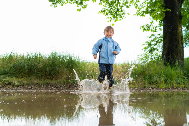 istock little boy jumping in rainwater puddle 1133352370