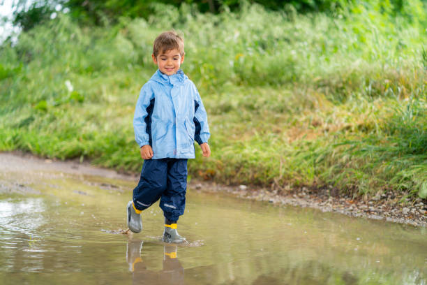 istock four years old cute boy walking through rain puddle 1133352387
