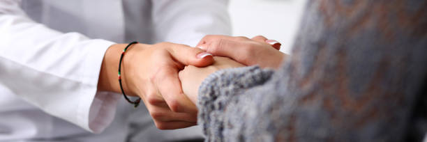 Friendly female doctor hold patient hand in office during reception Friendly female doctor hold patient hand in office during reception. Examination result, positive test, calm down, promise and cheer up, grief and suffer, treatment, condolence, ethics concept hospice photos stock pictures, royalty-free photos & images