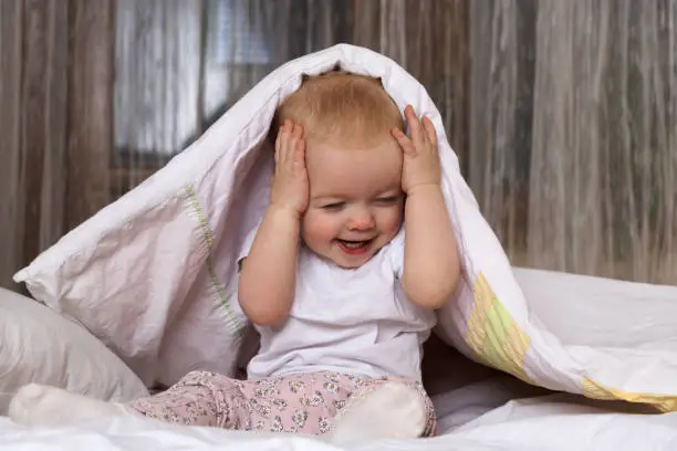 Photo of The kid is hiding under a blanket and laughing