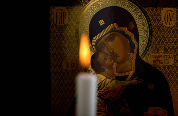 orthodoxe ikone der gottesmutter und des jesuskindes und eine verschwommene brennende kerze vor der ikone - orthodoxes christentum stock-fotos und bilder
