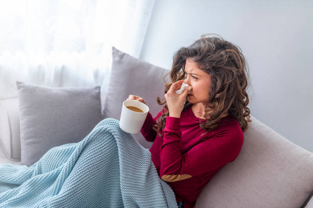 istock Young girl sick in bed with temperature drinks hot 1133361021