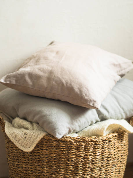 istock Wicker basket with a white soft knitted blanket and gray cushions against a white wall 1133365178