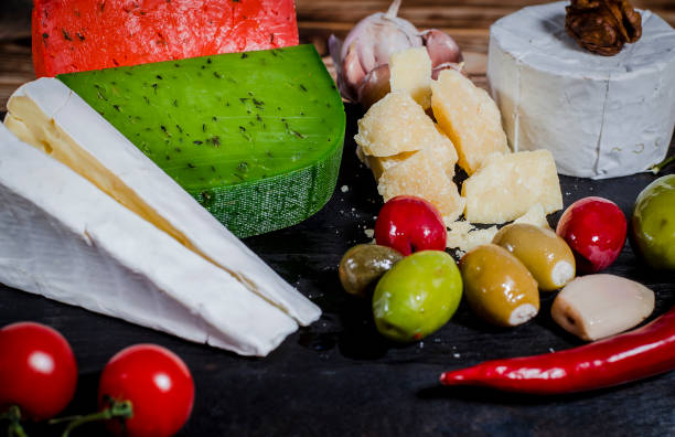 istock Mix cheese on dark background on wood board with grapes, honey, nuts, tomatoes and basil. Top view. 1133367995
