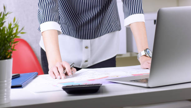 istock Real estate creative studio office. Architect woman working on architectural project for interior design. Woman's hands over the table with the drawing. 1133368246