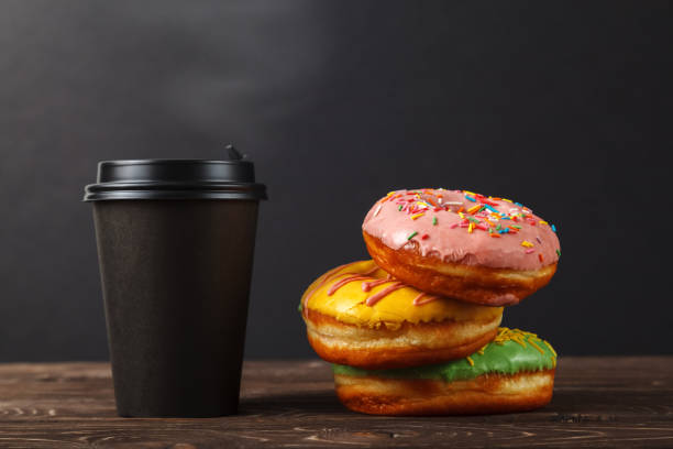 istock Colorful donuts and coffee in a black paper Cup on a black background. Bakery menu design concept. Hanukkah background. 1133368439