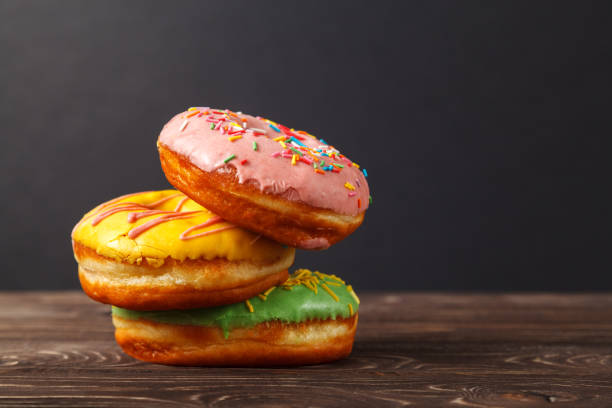 istock Three colorful donuts on a wooden table, on a black background. Bakery menu design concept. Hanukkah background. 1133368950