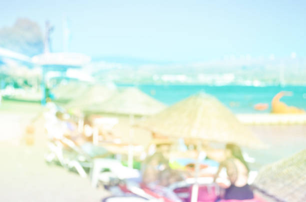 Abstract blurred image. People sunbathe and swim in the river on a sandy beach.
