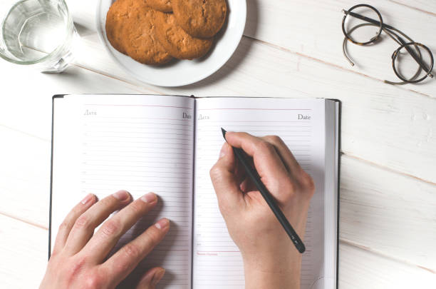 istock Man hands writing notes to the notebook on wooden table in home office 1133374927