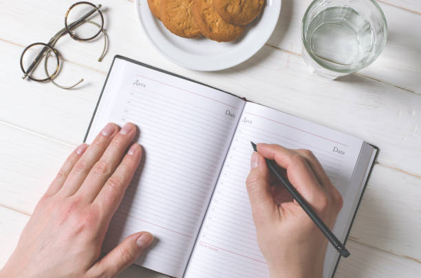istock Man hands writing notes to the notebook on wooden table in home office 1133374930