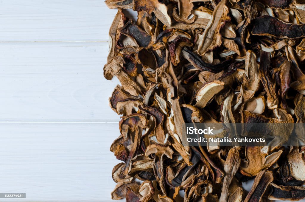 many dried mushrooms lies on a white wood desk many dried mushrooms lies on a white wood desk with copy space top view Agriculture Stock Photo