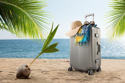 view of  suitcase with hat, pareo and sunglasses on sunny tropic beach