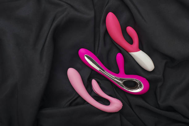 Stimulate your most sensitive area. Composition of colorful G-spot vibrators arranged on a black silk fabric. stock photo