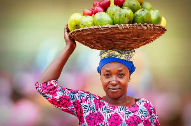 Portrait of Rwandan woman carrying on head wicker basket full of fruits