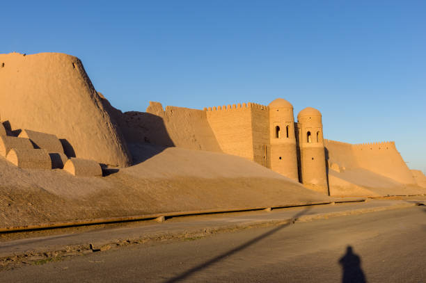 Khiva City Wall at sunset Shadow of a photographer in front of Ichan Kala city wall and south gate during sunset - Khiva, Uzbekistan khiva stock pictures, royalty-free photos & images