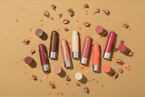 Lip balms with rose petals isolated on brown background (with clipping path)