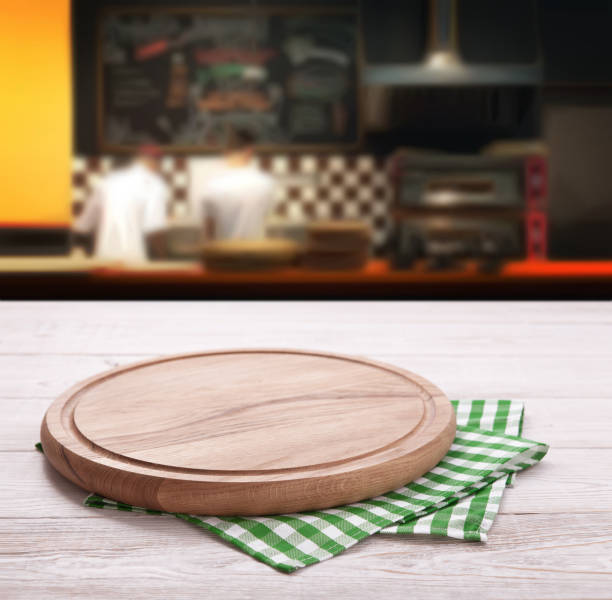 istock Empty pizza board with tablecloth on the table and pizzeria blurred background 1133388284