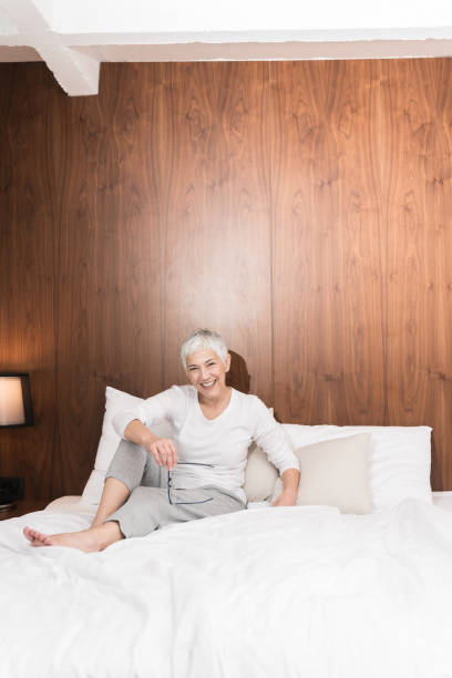 istock Senior cheerful woman sitting on a bed 1133389625