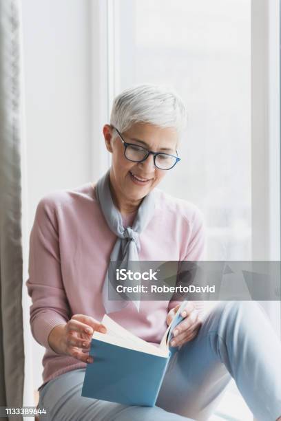 Mature Woman Reading Book Stock Photo - Download Image Now - Reading, Book, Women