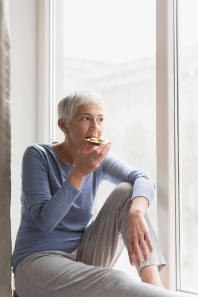 istock Woman eating breakfast by the window 1133389684