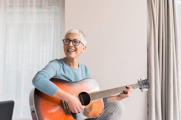 Smiling woman playing guitar Cheerful charming beautiful mature woman enjoy playing guitar, Musical hobbies concept music theory stock pictures, royalty-free photos & images