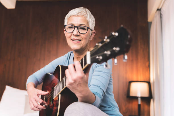 Woman playing guitar Portrait of beautiful mature woman playing guitar in cosy modern apartment, Free time hobbies music and art concept hobbies stock pictures, royalty-free photos & images