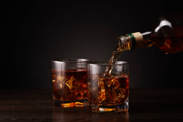 bottle of whisky and two glasses. pouring - action alcohol alcoholism bar imagens e fotografias de stock