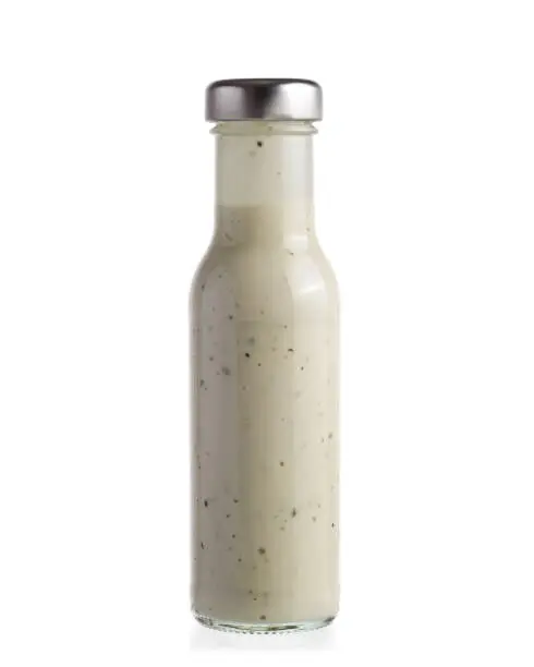 Salad dressing in glass bottle isolated on white background.