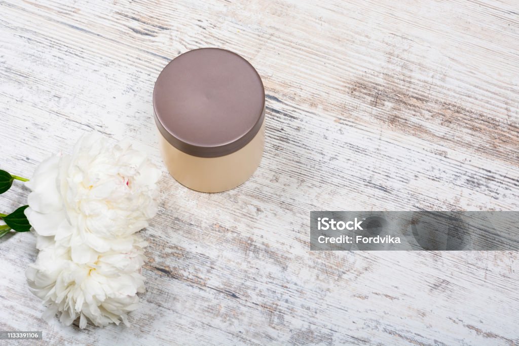 Body and hair cosmetics, peonies on wooden background Beige mocap can for cream after skin care face and body and flowers peonies lying on a battered texture light wooden table, top view, top angle, close-up, space for text, Flat Lay,  Copy space Backgrounds Stock Photo