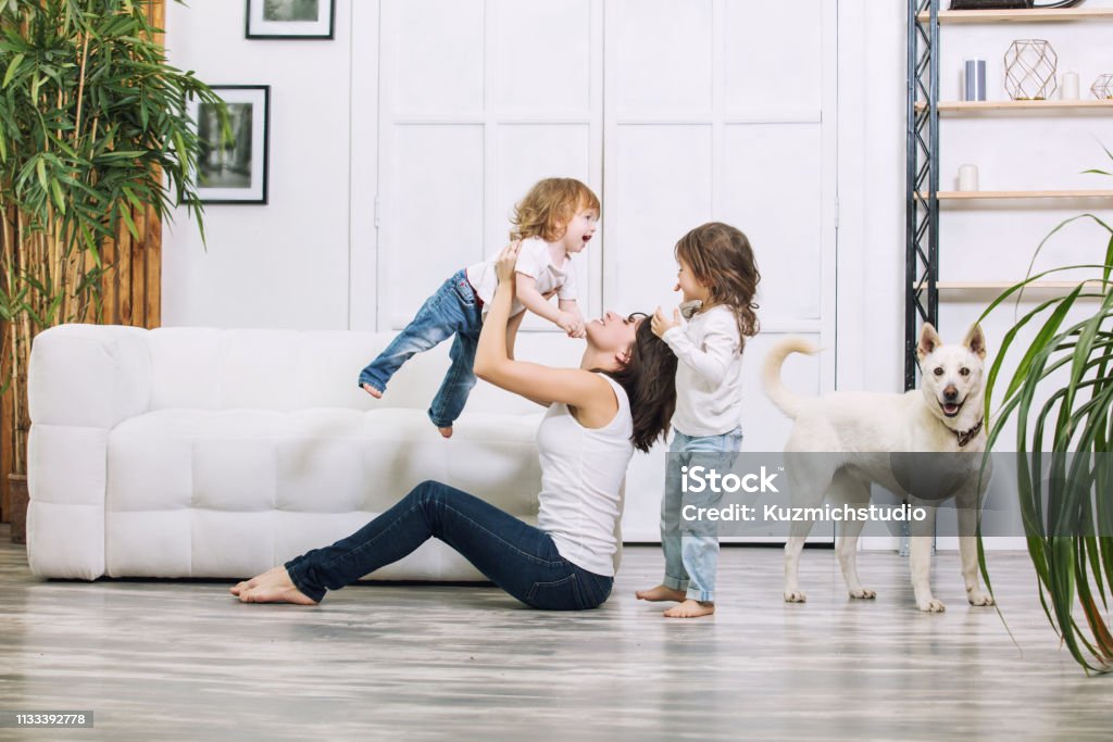 Le bambine sono belle e carine con madre e cane da compagnia a casa insieme felici - Foto stock royalty-free di Famiglia