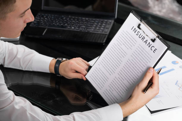 jeune homme se familiariser avec les termes de l'assurance dans le bureau lumineux - insurance agent photos et images de collection