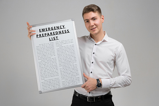 Emergency preparedness list in the hands of a confident man in a white shirt. Handwriting text writing Emergency preparation and Response Adviser. Concept meaning Be prepared for emergencies