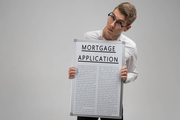 istock Young man keeps in front of him poster with mortgage application isolated on light background 1133396106