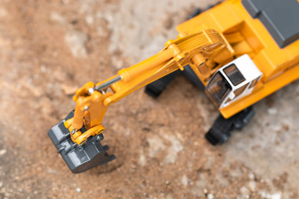 istock Top view of Yellow excavator model toy performs excavation work on a construction site. 1133399248