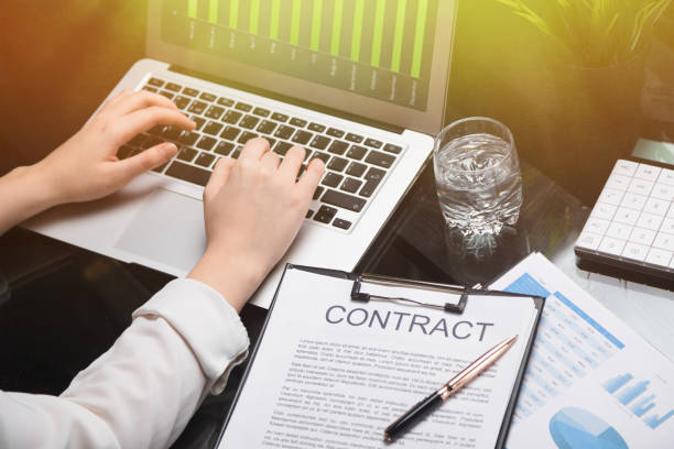 istock Closeup of hands typing on laptop lying next to contract 1133402618
