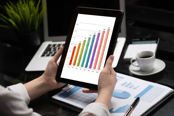 istock Close-up hands holding tablet on background of financial documents 1133402626