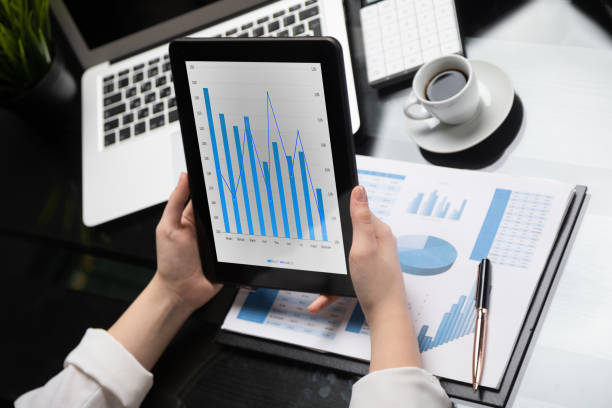 istock Close-up hands holding tablet on background of financial documents 1133402631