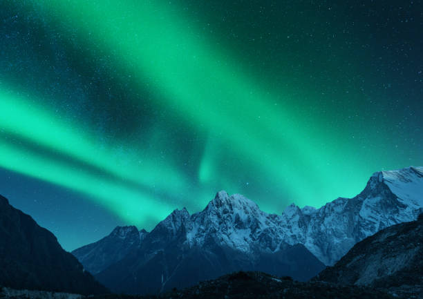 Aurora borealis above the snow covered mountain range in europe. Northern lights in winter. Night landscape with green polar lights and snowy mountains. Starry sky with aurora over the rocks. Space Aurora borealis above the snow covered mountain range in europe. Northern lights in winter. Night landscape with green polar lights and snowy mountains. Starry sky with aurora over the rocks. Space brightly lit winter season rock stock pictures, royalty-free photos & images