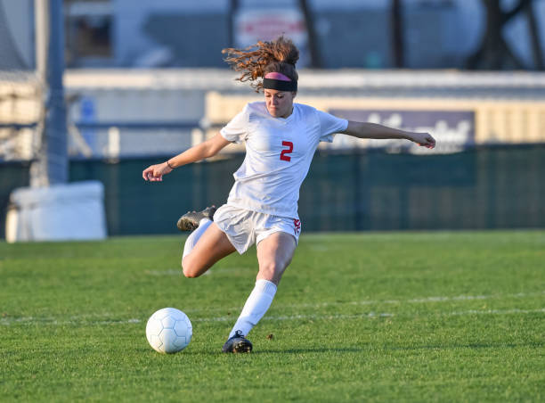 Young athletic girl playing with a soccer ball in a green grass field Very athletic young girl kicking and dribbling the soccer ball on a grassy green field. kicking stock pictures, royalty-free photos & images